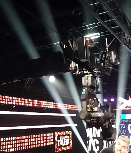 A camera suspended on a line in a dark room with LED walls in the background